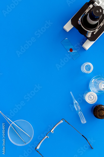 Clinical science research with microscope. Laboratory equipment on blue background top view copy space