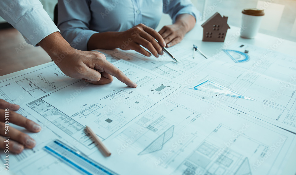 Architects engineer working with blueprints on table and discussing project together at the meeting in the office. Architects engineer working with blueprints on table and discussing project together at the meeting in the office.