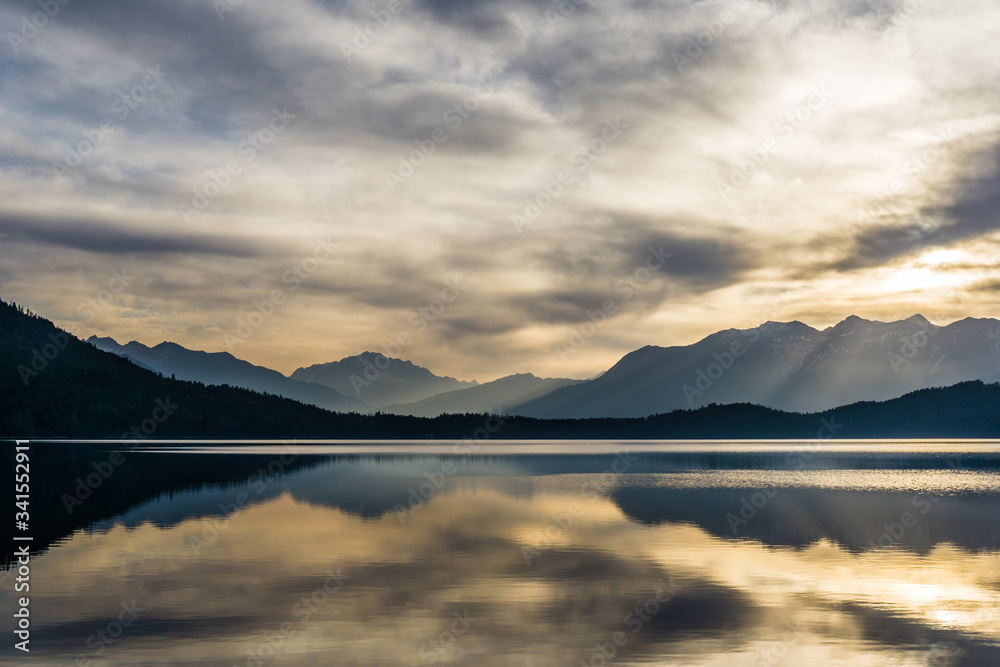 Colorful reflections of hills, sky and forest on the calm surface of Rara Lake during sunrise. Pristine Rara lake is the largest lake of Nepal gaining popularity as a travel destination in Karnali.