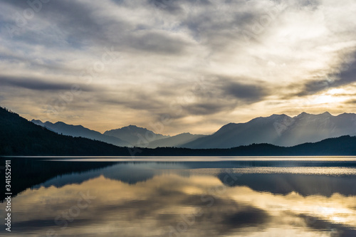 Fototapeta Naklejka Na Ścianę i Meble -  Colorful reflections of hills, sky and forest on the calm surface of Rara Lake during sunrise. Pristine Rara lake is the largest lake of Nepal gaining popularity as a travel destination in Karnali.