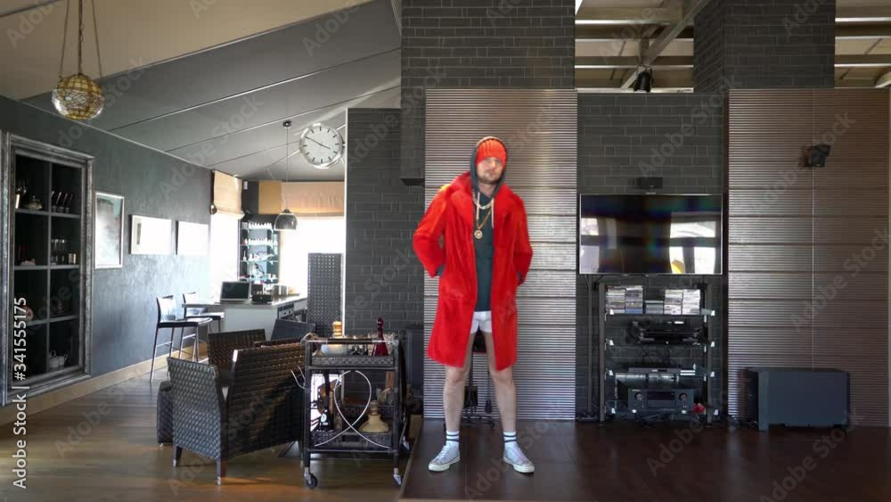 Young unusual guy funny dressed in a red coat with a gold chain on his neck and in his underpants, he is fooling around at home on self-isolation and so entertains himself and the audience TikToks Young unusual guy funny dressed in a red coat with a gold chain on his neck and in his underpants, he is fooling around at home on self-isolation and so entertains himself and the audience TikToks