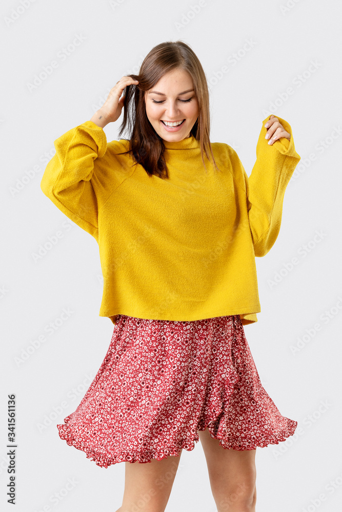 Cheerful woman wearing a mustard yellow sweater on a red flower dress Cheerful woman wearing a mustard yellow sweater on a red flower dress