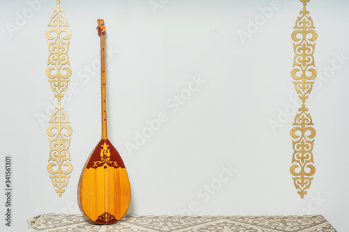 Kazakh national musical instrument dombra on a white background. National Kazakh decor gold ornaments and household items. Kazakh Kyrgyz ethnic background photo