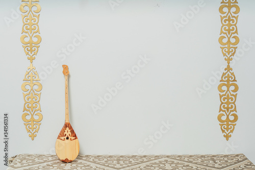 Kazakh national musical instrument dombra on a white background. National Kazakh decor gold ornaments and household items. Kazakh Kyrgyz ethnic background photo