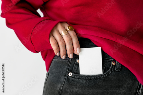 Woman keeping a white card in a pocket of her jeans
