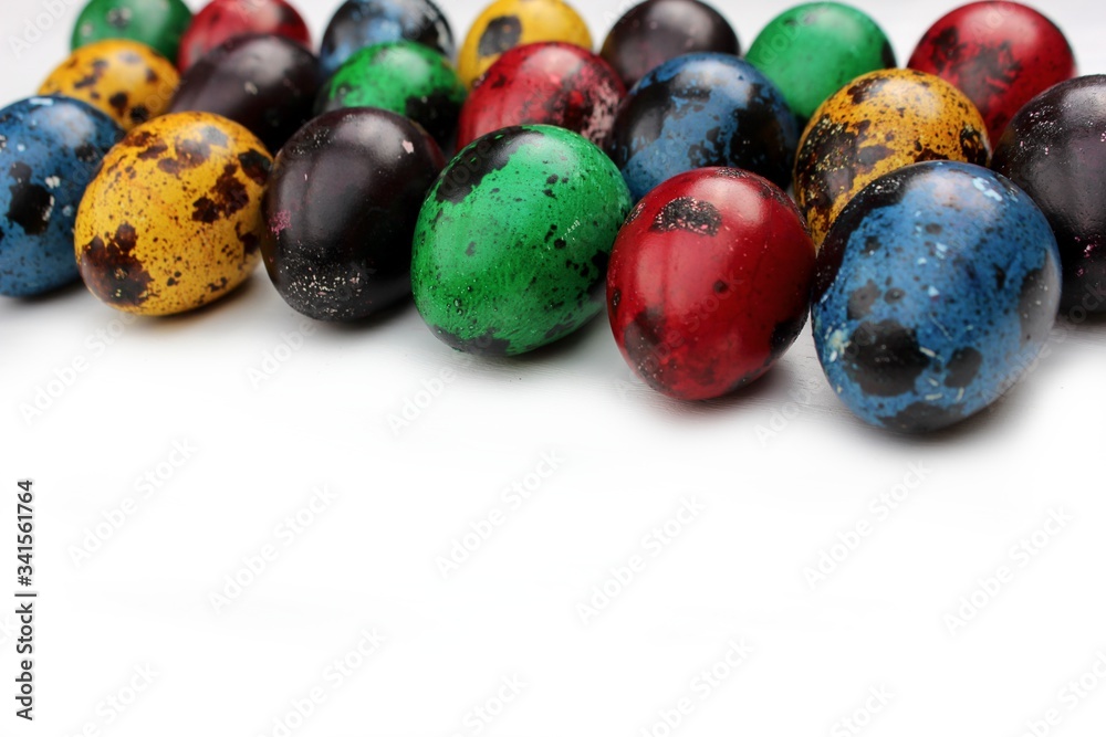 Frame of multi-colored quail eggs. Multi-colored quail Easter eggs on a white background. Multi-colored eggs are located at the top with a place for text. Dietary food.