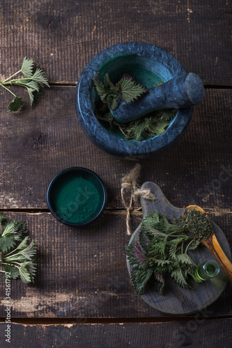Fresh stinging nettle leaves on wooden table.Urtica dioica oil with spirulina powder  a healthy supplement to improve health.