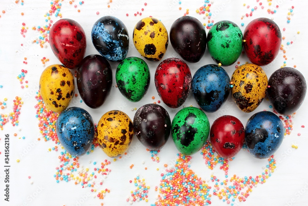 Multi-colored eggs close-up on pastry topping, top view. Set of easter eggs isolated on white. Easter background. Blue, red, green, yellow, purple quail eggs.