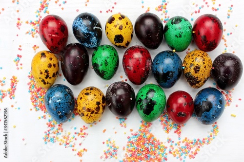 Obraz na płótnie Multi-colored eggs close-up on pastry topping, top view. Set of easter eggs isolated on white. Easter background. Blue, red, green, yellow, purple quail eggs. w salonie
