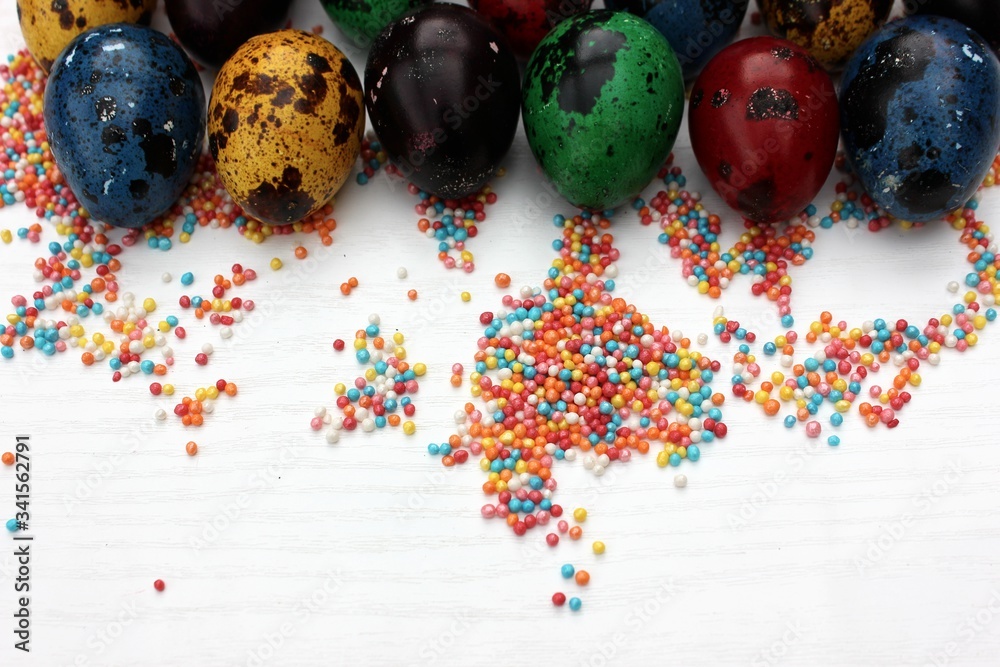Multi-colored eggs close-up on pastry topping, top view. Set of easter eggs isolated on white. Easter background. Blue, red, green, yellow, purple quail eggs.