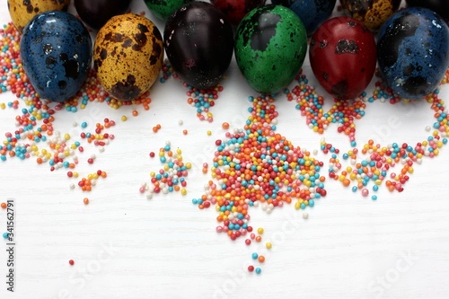 Obraz na płótnie Multi-colored eggs close-up on pastry topping, top view. Set of easter eggs isolated on white. Easter background. Blue, red, green, yellow, purple quail eggs. w salonie