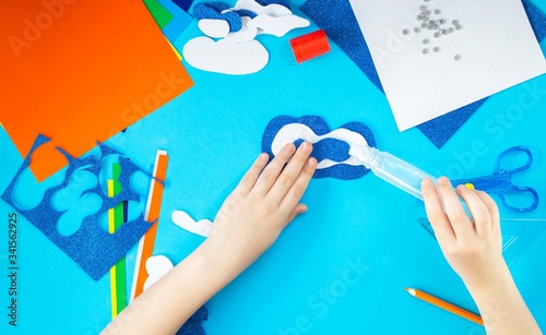 DIY. The creative process. Children's hands stick various shapes from bright colored paper. Classes with the child at home, in kindergarten or school in elementary grades. Master class. Step 3