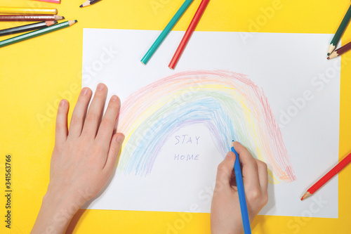 Kid painting rainbow during Covid-19 quarantine at home. Stay at home Social media campaign for coronavirus prevention, let's all be well, hope during coronavirus pandemic concept photo