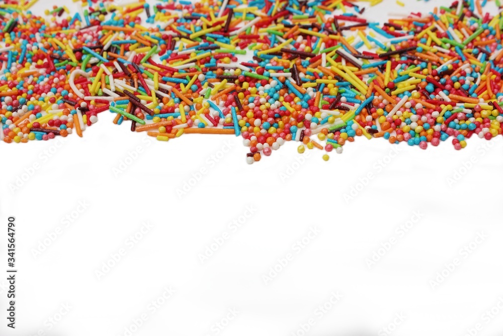 confectionery powder for decorating cupcakes and cakes. Decorative sprinkles border on white background. Multicolor Sugar confectionery powder in the corner. Scattered sweet sugar sticks and balls.