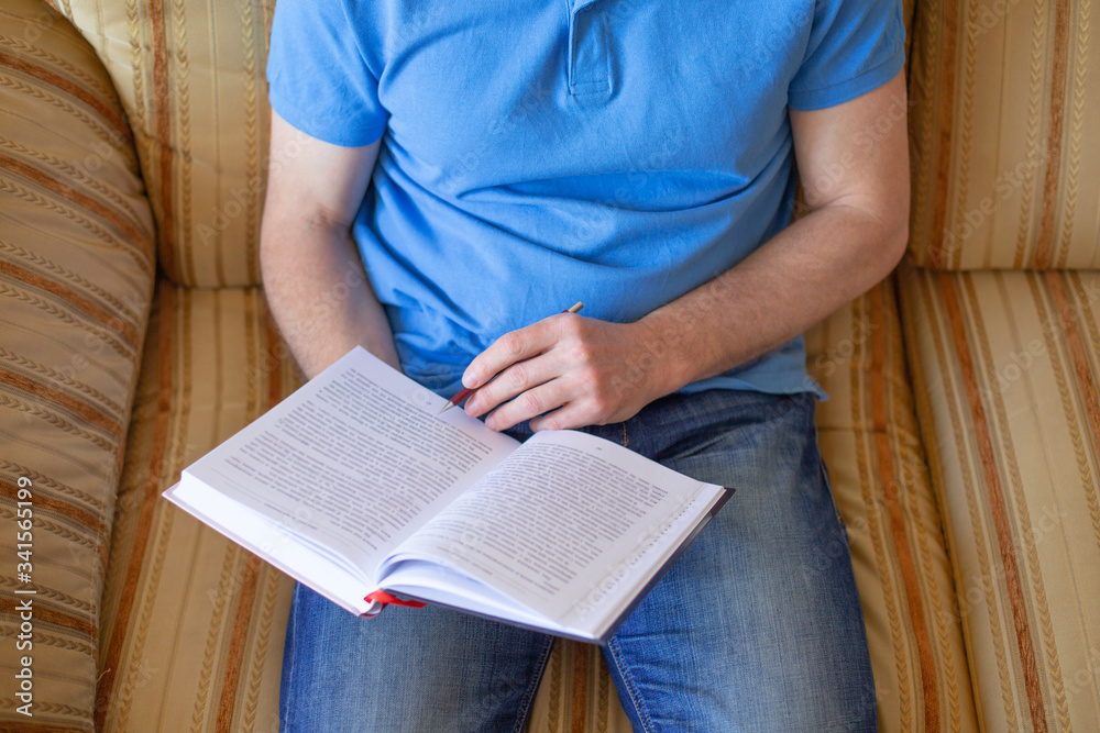 Obraz premium man sitting on couch and reading book at home.