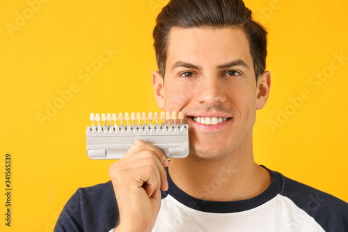 Man with teeth color samples on yellow background