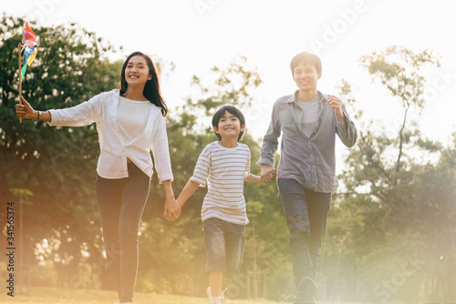 Scene of Asian happy family spend time together walking and relaxing at the park in the afternoon autumn, concept family togetherness, warm hearted family, parenthood, happy time family outing.
