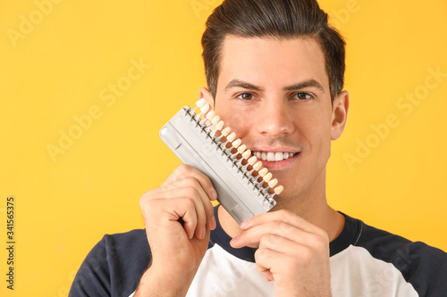 Man with teeth color samples on yellow background
