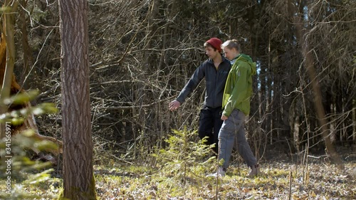 Happy couple walking in the forest in early spring. Sunny weather, bare trees, green fir-trees. Healthy lifestyle concept
