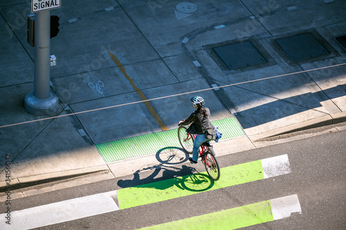 Fotografía Woman in a helmet rides a bicycle crosses the road at a crossroads at a pedestri