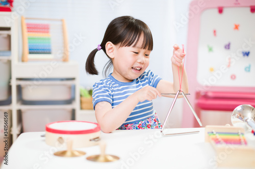 toddler girl play triangle at home for homeschooling photo