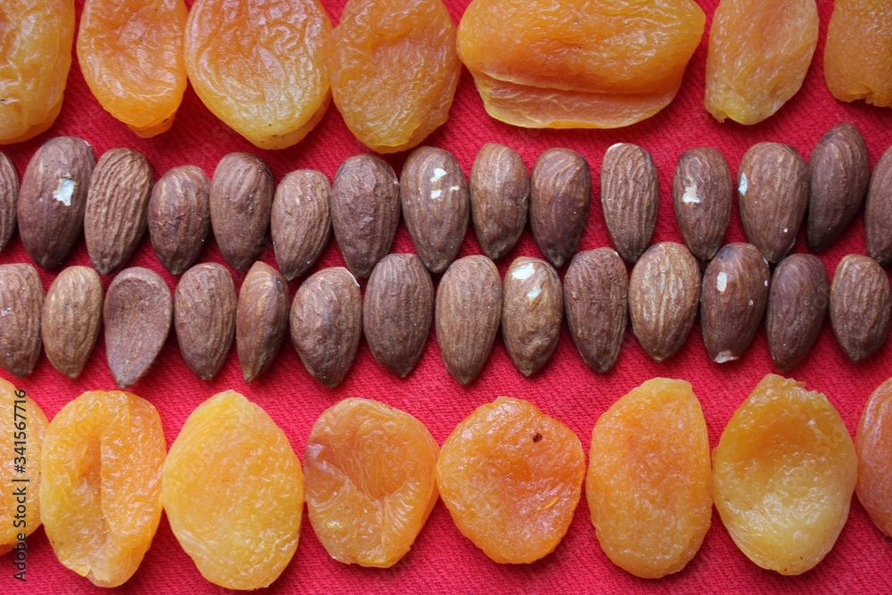 Almonds and dried apricots lined with a line on a red background. Almonds and dried apricots close-up with place for text. Nuts and dried fruits, healthy nutrition.