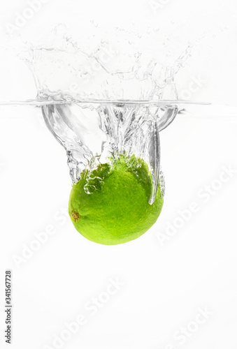Falling of fresh lime into water against white background