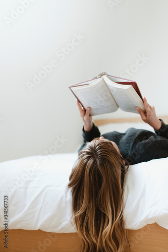 Woman reading a book on her bed during coronavirus quarantine