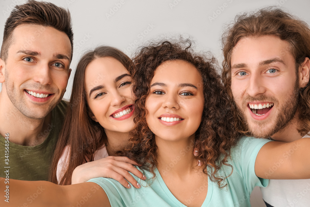 Friends taking selfie on grey background