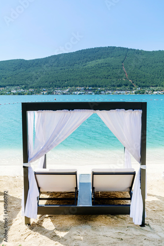 Luxury Sunbeds with White Curtains on the Beach .Summer Holiday Concept