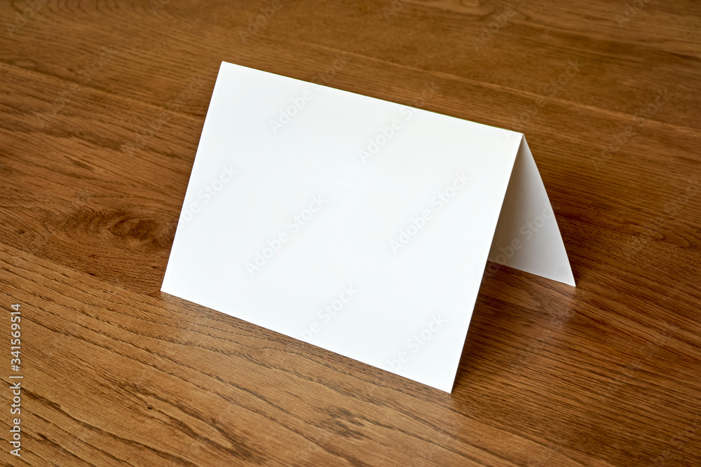 Standing blank empty greeting card mock up on dark wooden background. For use as a Christmas, birthday, wedding or celebration background template. Standing blank empty greeting card mock up on dark wooden background. For use as a Christmas, birthday, wedding or celebration background template.