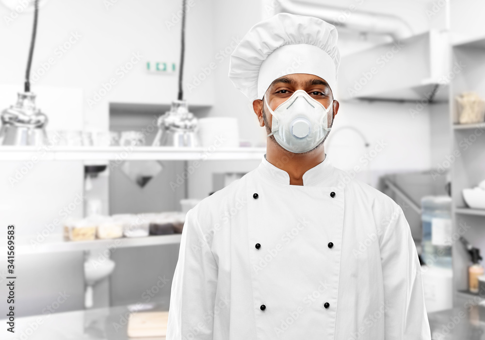 health protection, safety and pandemic concept - indian male chef cook wearing face protective mask or respirator over restaurant kitchen background health protection, safety and pandemic concept - indian male chef cook wearing face protective mask or respirator over restaurant kitchen background