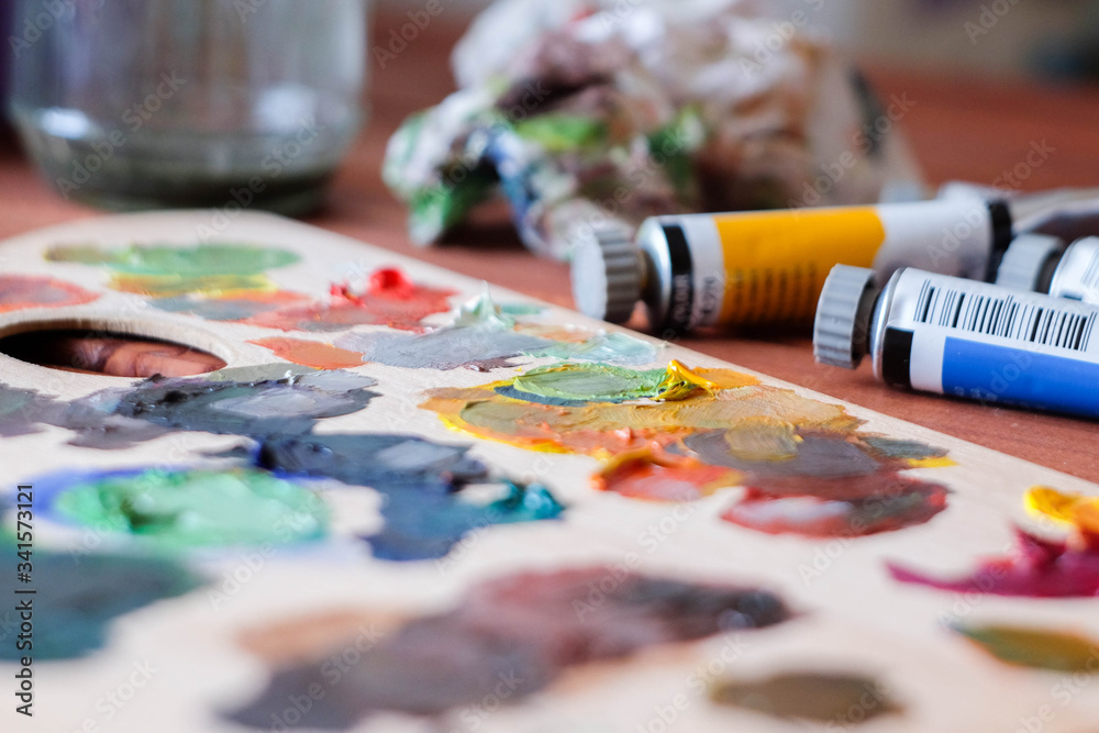 Close up oil painting process. Oil paints palette. Oil painting tools on the wooden table. Painter work place. Paint tubes. Close up oil painting process. Oil paints palette. Oil painting tools on the wooden table. Painter work place. Paint tubes.