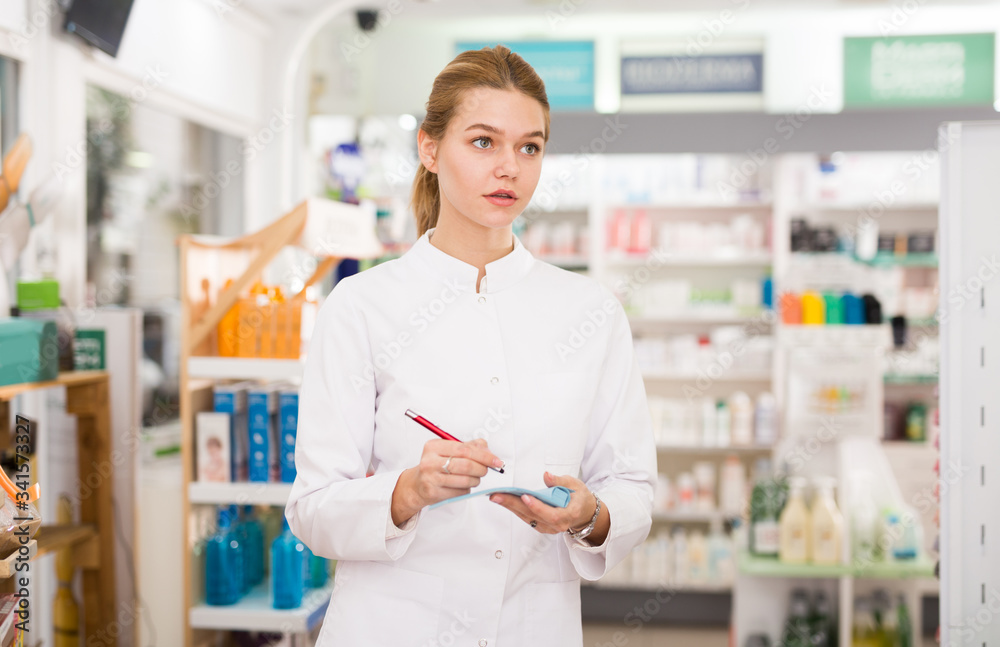 Pharmacist is writing down assortment of drugs in pharmacy