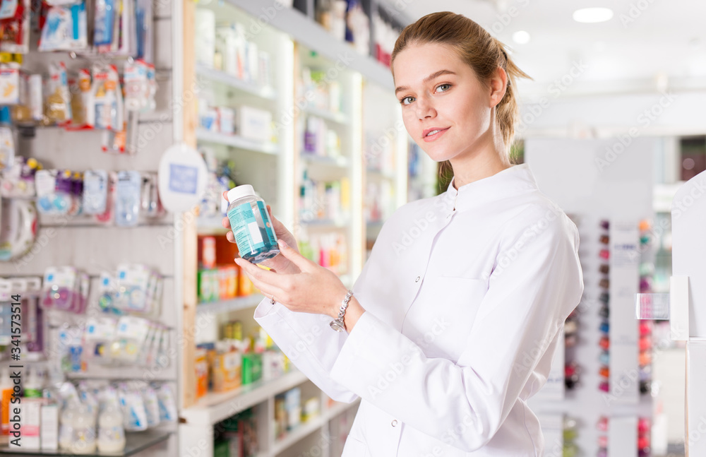 Young friendly pharmacist offering reliable medicine in pharmacy