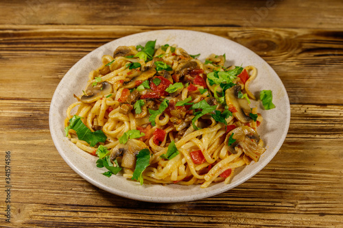 Pasta with mushrooms and tomato sauce on wooden table