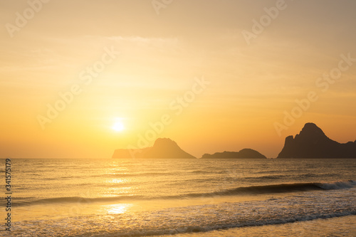 Seascape sunrise with mountain and smooth waves in the morning.