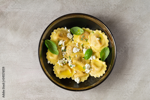 Girasoli pasta with soft cheese, olive oil and basil leaves in black bowl isolated on grey background. Italian, Mediterranean lunch or dinner.  Top view.  photo