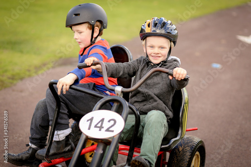 Happy little boys riding two person pedal cart at caravan park in winter