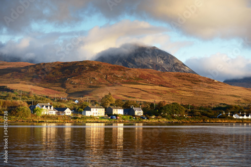Panoramic view of the valley near the Paps of Jura under the colorful stormy sunset sky. Traditional country houses close-up. Dramatic cloudscape. Jura island, Inner Hebrides, Scotland, UK photo