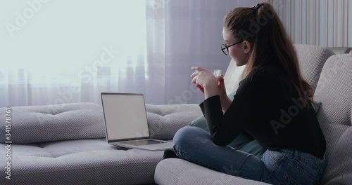 girl working on laptop at home on sofa and drinking tea. stay at home and work remotely. isolation at home.