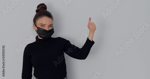 girl in a protective mask on a simple light background. removes and puts on the mask. protection against viruses and dirty air.