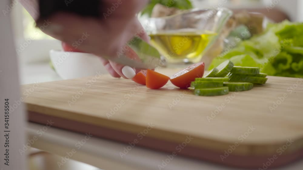 Extreme close-up of female hands cutting tomatoes. Unknown young Caucasian woman slicing vegetables for salad. Restaurant business, homemade food, healthy eating, lifestyle. Extreme close-up of female hands cutting tomatoes. Unknown young Caucasian woman slicing vegetables for salad. Restaurant business, homemade food, healthy eating, lifestyle.