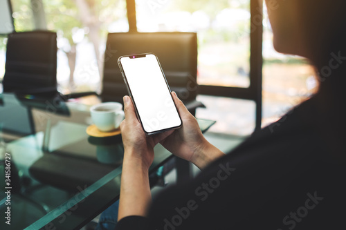 Mockup image of a woman holding mobile phone with blank white screen in office