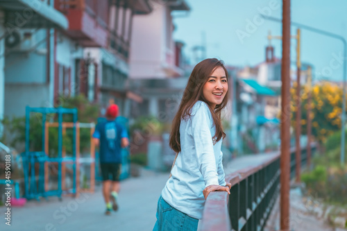 smile happy girl in good morning time on the road with blur village by her wearing shirt white and jeans