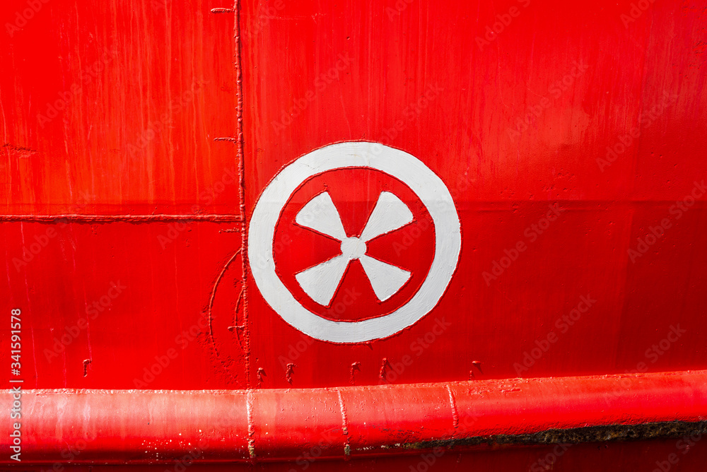 Steel Hull of red vessel in water with detail of a ship's hull markings