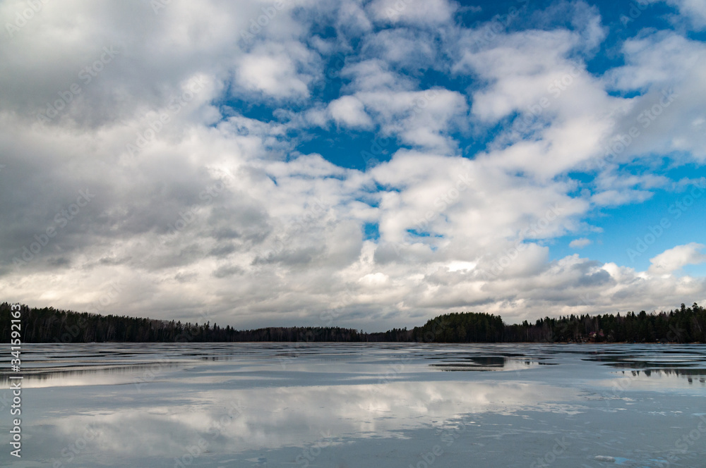 winter landscape with a frozen lake and clouds above it