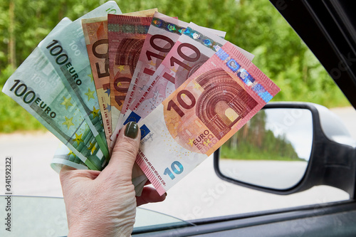 Euro banknotes of various denominations in a woman hand inside of a car