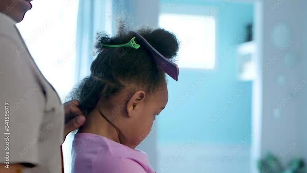 Mid-close up of African American girl getting her hair braided at home during the stay at home ordinance. Mid-close up of African American girl getting her hair braided at home during the stay at home ordinance.