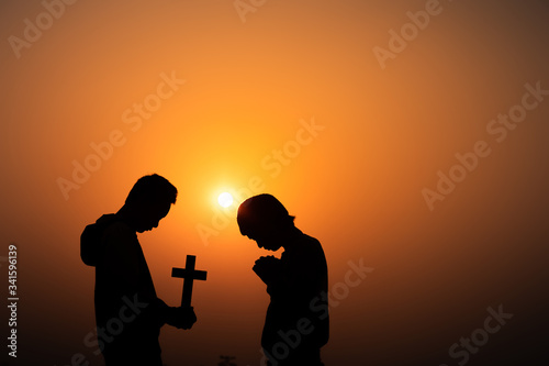 Two christian praying in morning time with sun light background, Christians should worship and thank God, christian silhouette concept.